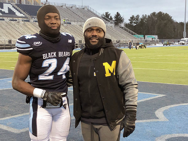 Jean Guillaume and former player Katley Joseph, pose for a photo at the University of Maine football field.