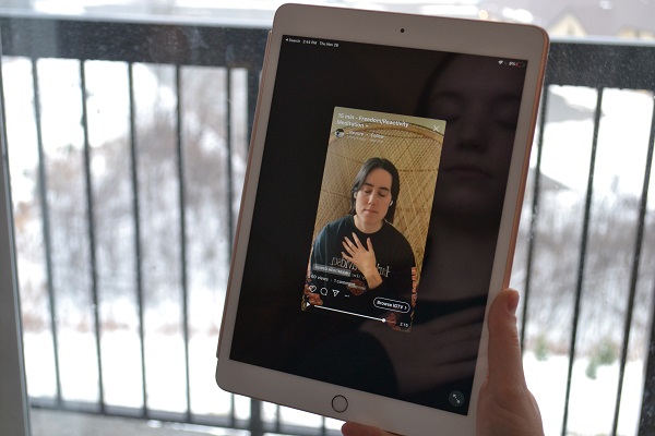 Girl holding an iPad and meditating to a guided meditation video.