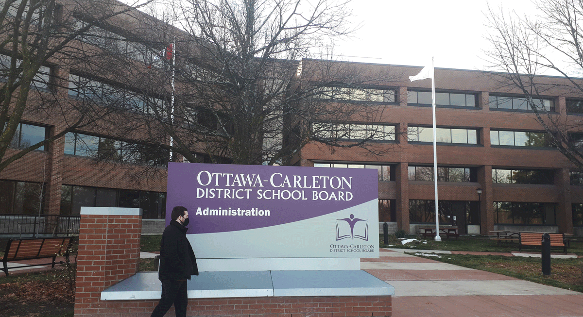 A man is standing next to the Ottawa-Carleton District School Board (OCDSB) in Ottawa.