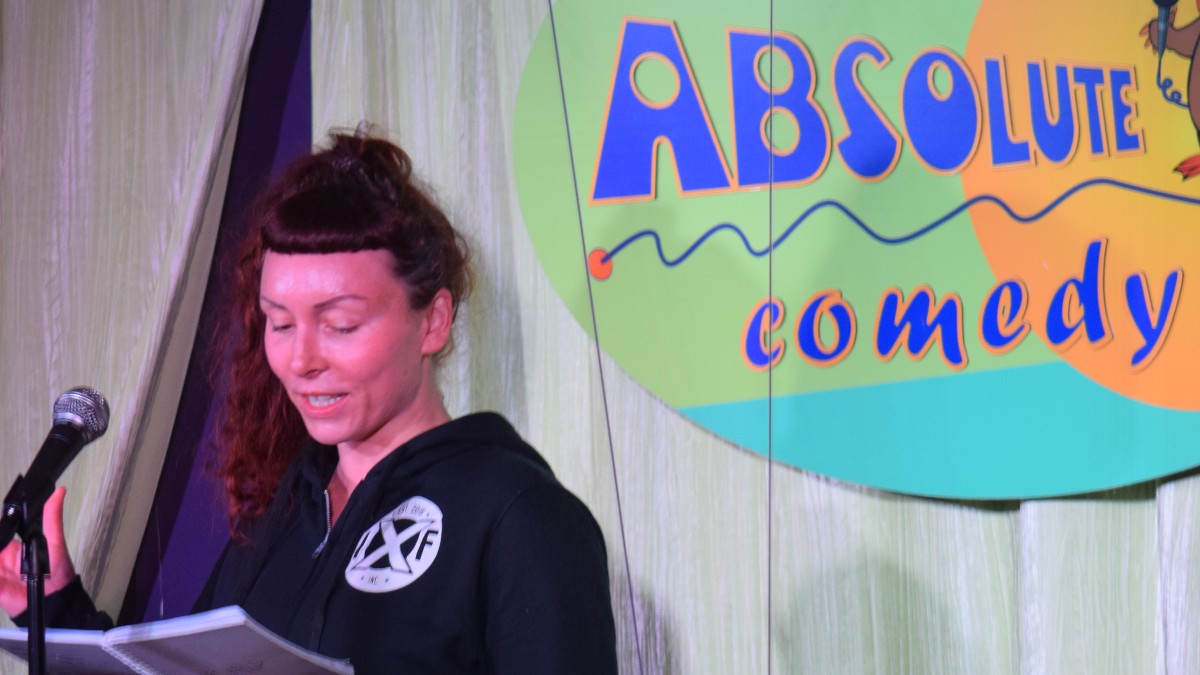 Woman reading stand-up material on stage.