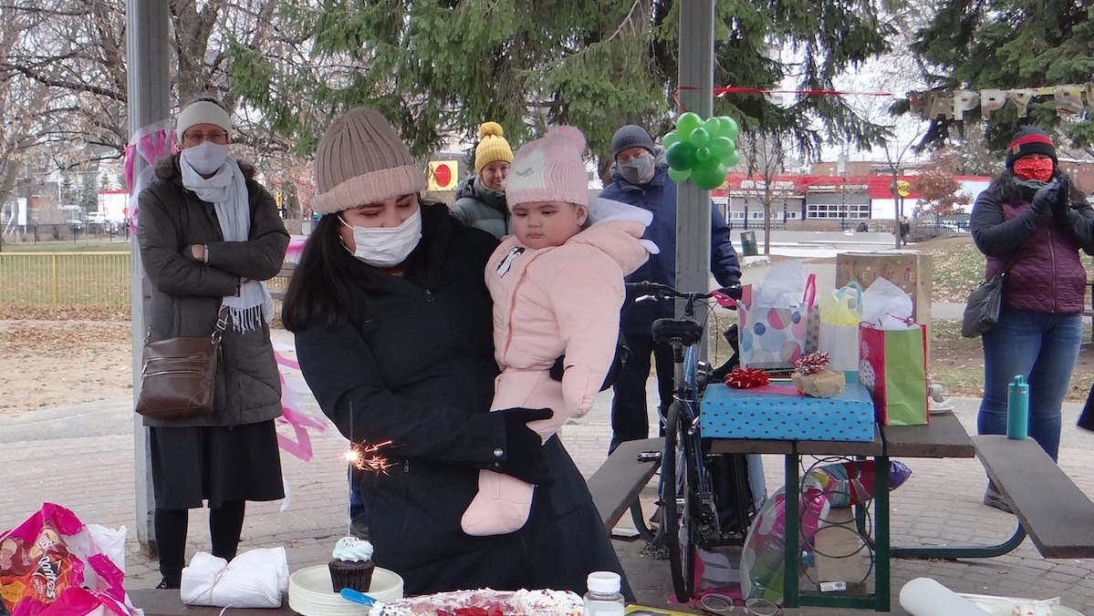 A birthday party is held outside for a young refugee girl.