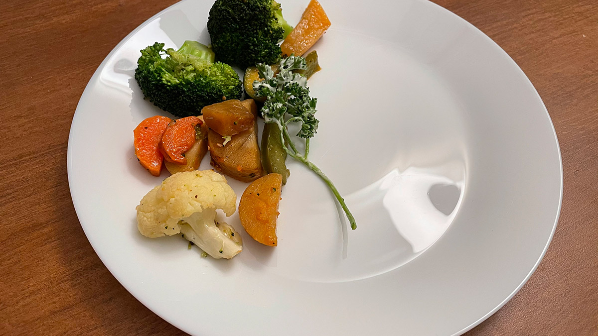 A half-empty plate with assorted vegetables on it.