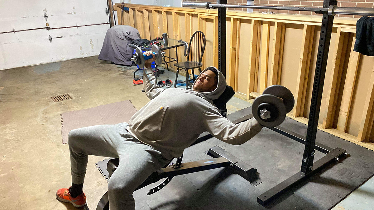 football player lifts weights in garage