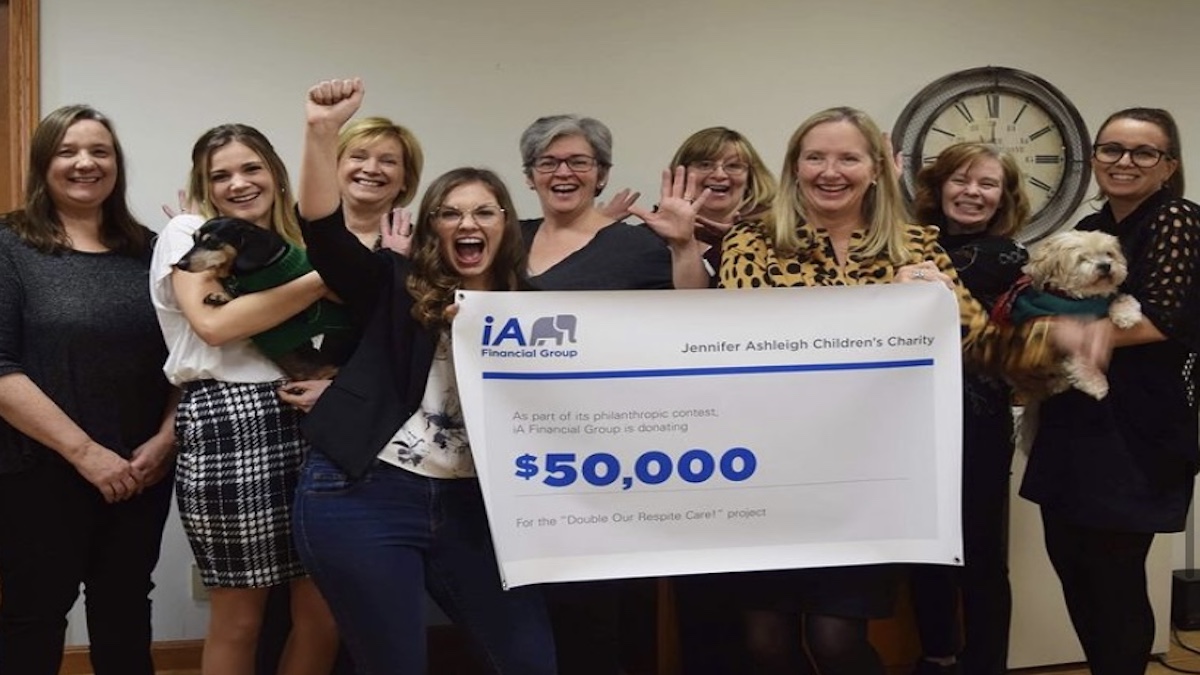 Children's charity volunteers and staff happily receive a cheque from a philanthropy contest.