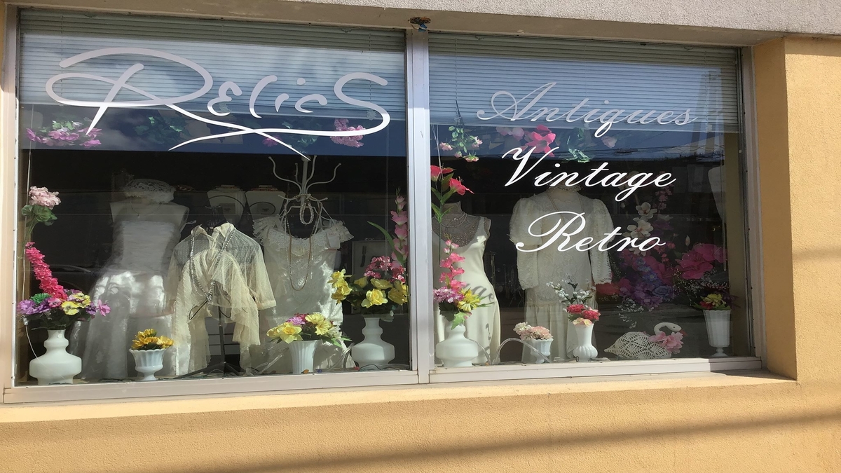 Various vintage white dresses posed in a store front window.