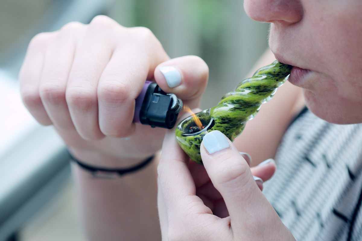 A cannabis user is smoking from a pipe.