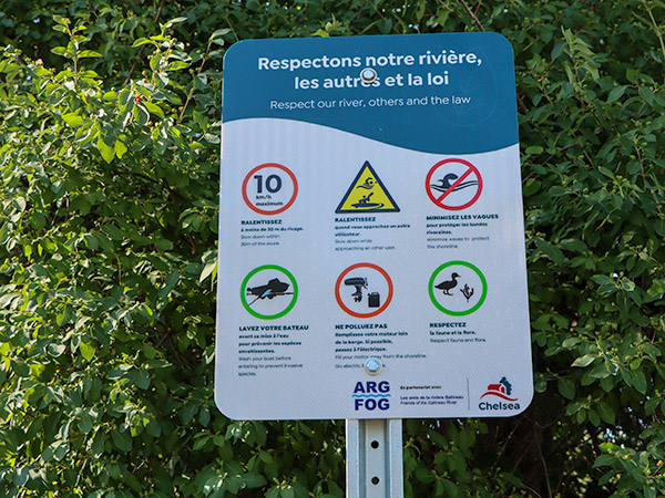 A sign informing boaters about speed limits to reduce wake and other rules for boating on the Gatineau River.