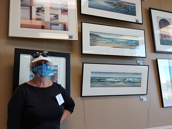 Anne Remmer Thompson stands in front of five watercolour paintings.