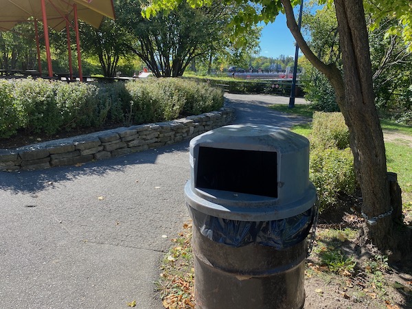 Single trash can near a pedestrian path in Hog's Back Park.