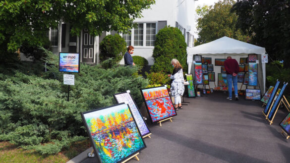 Art displayed in driveway, 2 visitors looking at art.