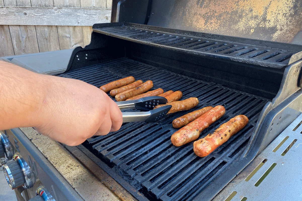 Tom Lingard cooking hotdogs on the barbecue.