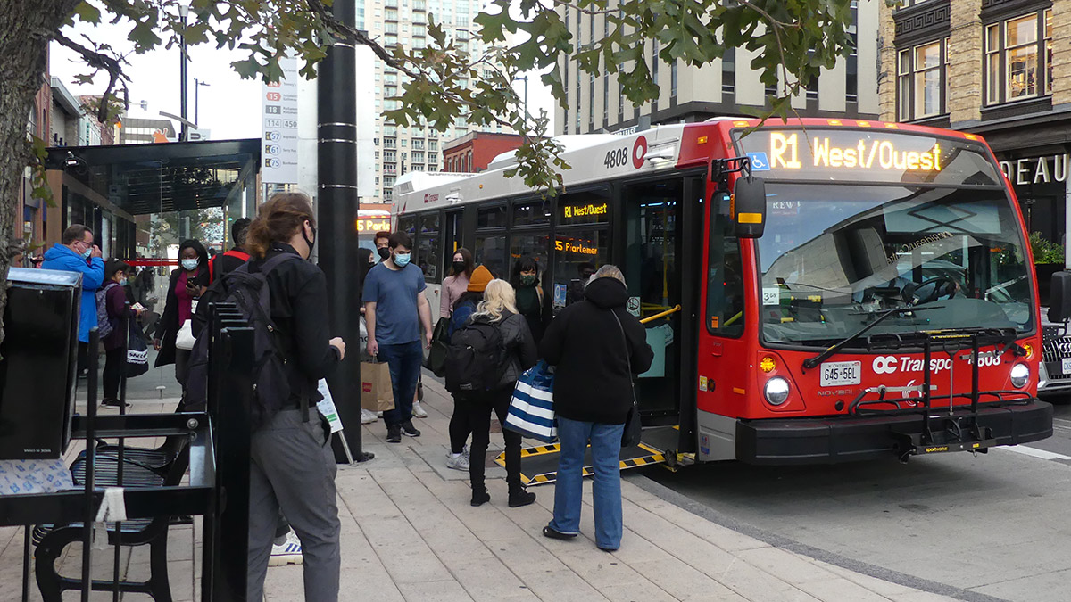 Citizens board an R1 bus on Rideau Street.