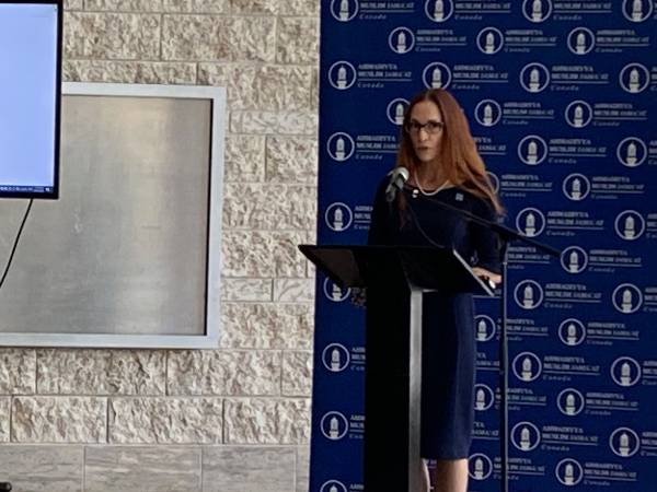 Laura Dudas, Deputy Mayor of Ottawa, standing at a podium with a blue background, delivering a speech at the Islamic Heritage Month event.