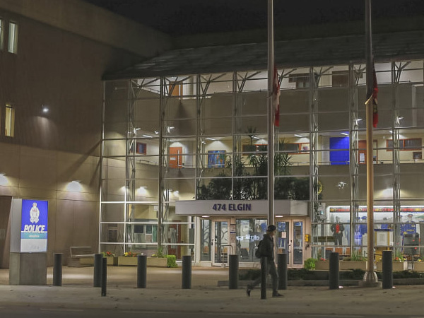 The Ottawa police headquarters at Elgin street's front entrance is shown at night as a person walks on the sidewalk in front