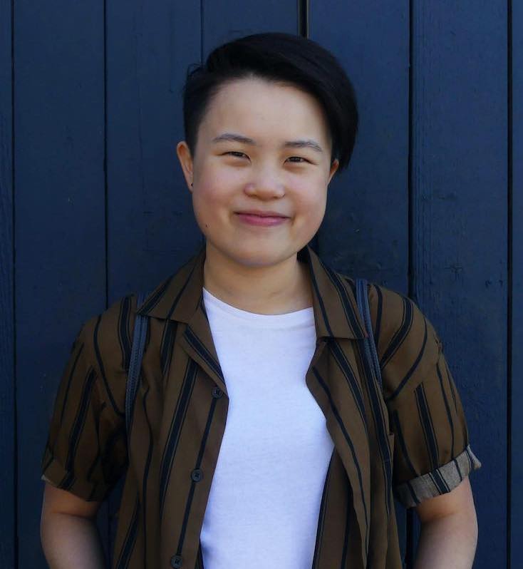 Tobin smiling and standing in front of a blue wood-paneled wall