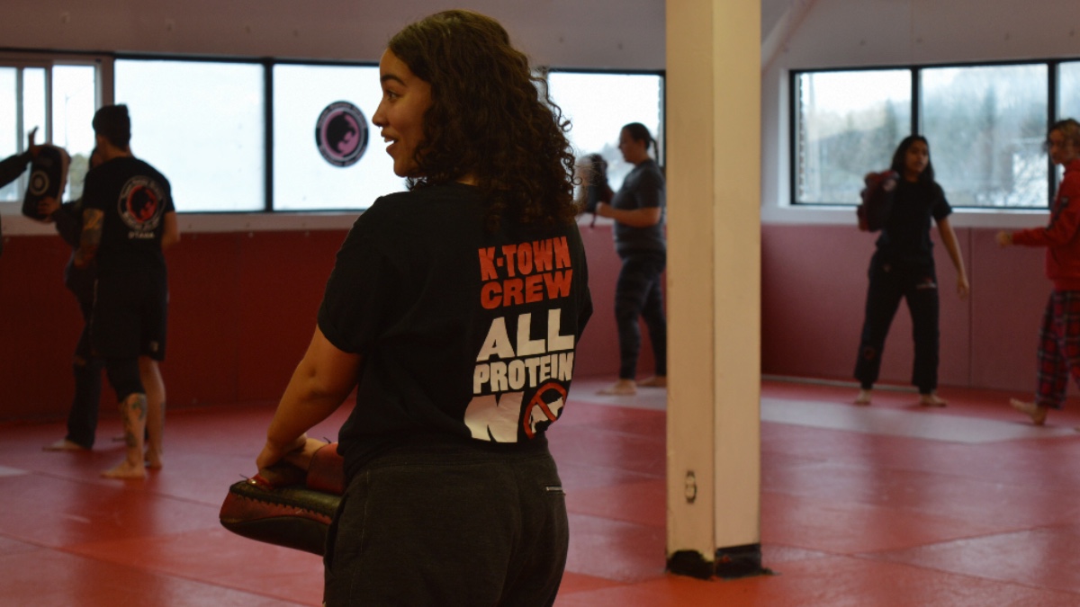 Isabella Griffin looking to the left with smile on her face. She is surrounded by other participants in the background who are blurred. 