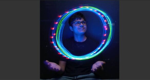 Jaden Bhimani, centre, surrounded by rings of red, blue and green light, with hands open underneath.