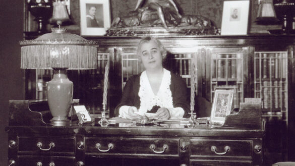 Lillian Bilsky Freiman sits at her desk in a crowded office space. A lamp sits prominetly on the desk.