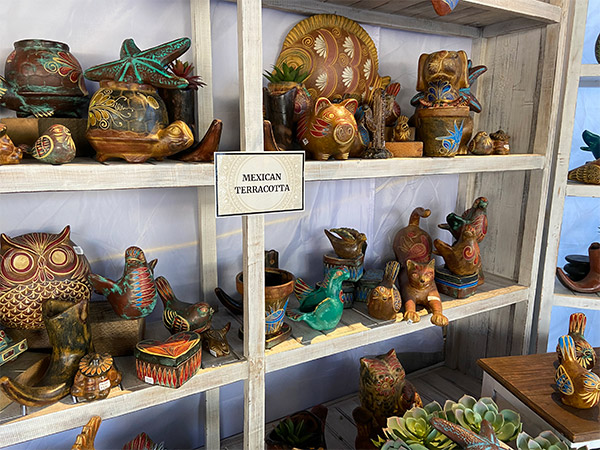 Hand-painted terracotta decorations on a shelf include an owl, birds, a pig, a cat, hens, etc.