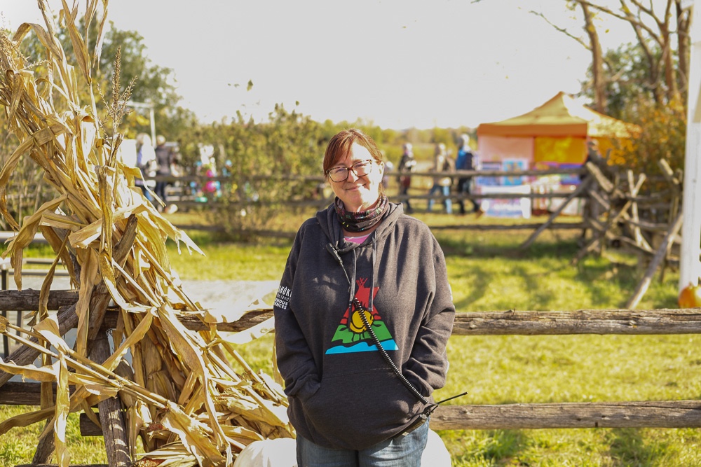 Executive Director and owner of Indigenous Experiences, Trina Simmard is pictured smiling beside a large bunch of corn husks. 