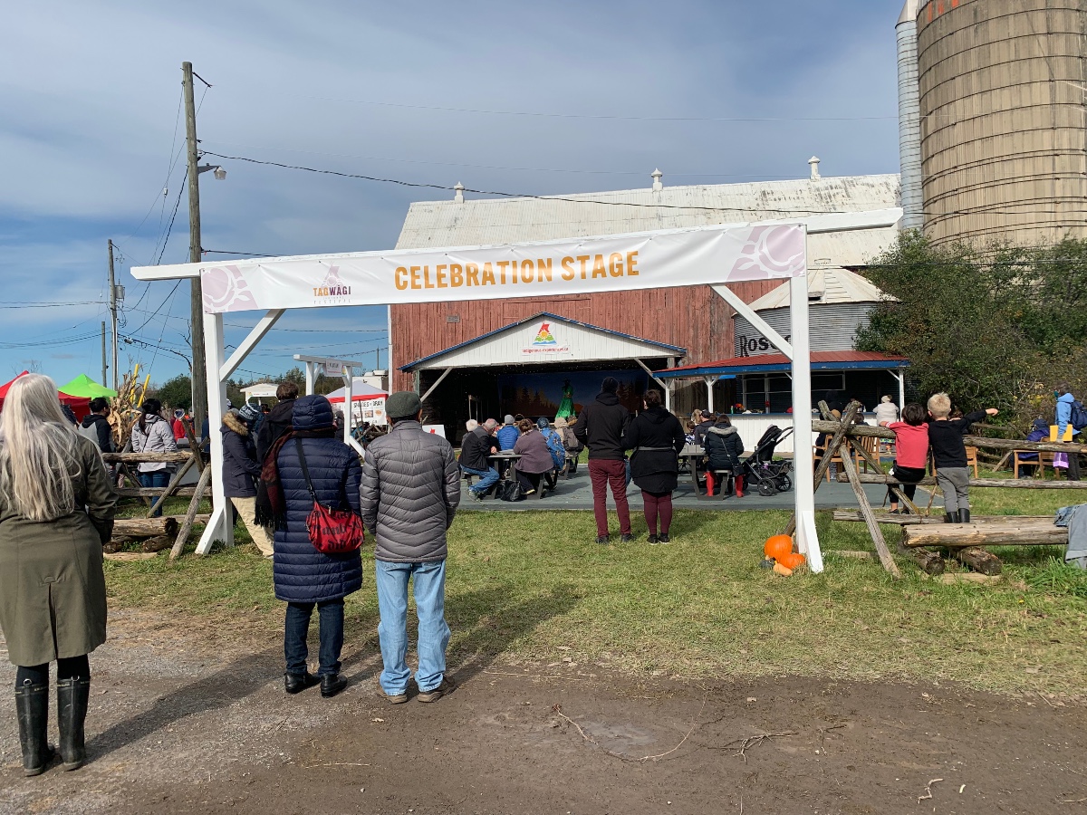 Celebration stage is pictured with dozens of people milling about. Celebration stage is where the pow wow dance and story telling took place. 