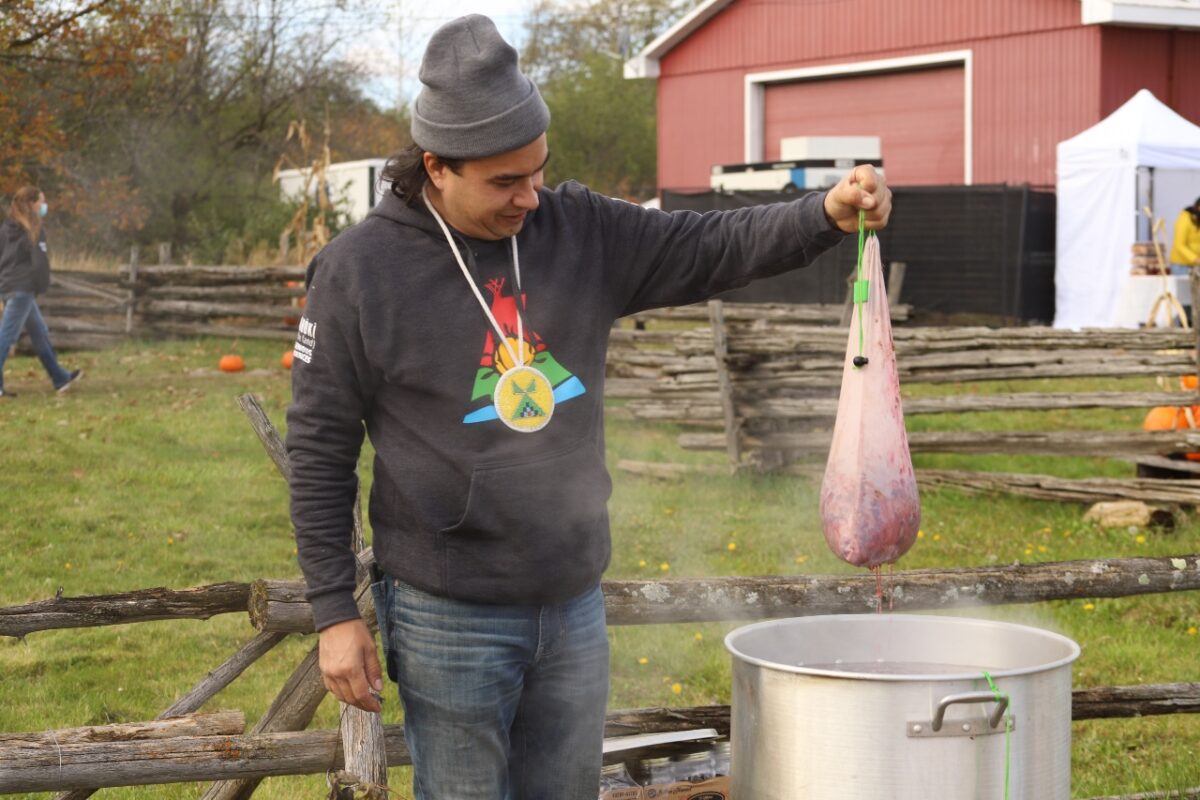 Chef Paul Owl is pictured brewing a traditional ten ingredient tea for festival goers to enjoy. He is holding a mesh steeping bag with the tea ingredients, which was just removed from the boiling water. 