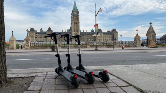 Three Bird e-scooters parked in front of the Parliament Building.