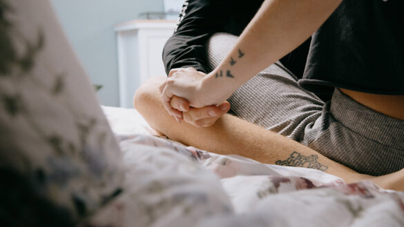 Couple holding hands while sitting on a bed