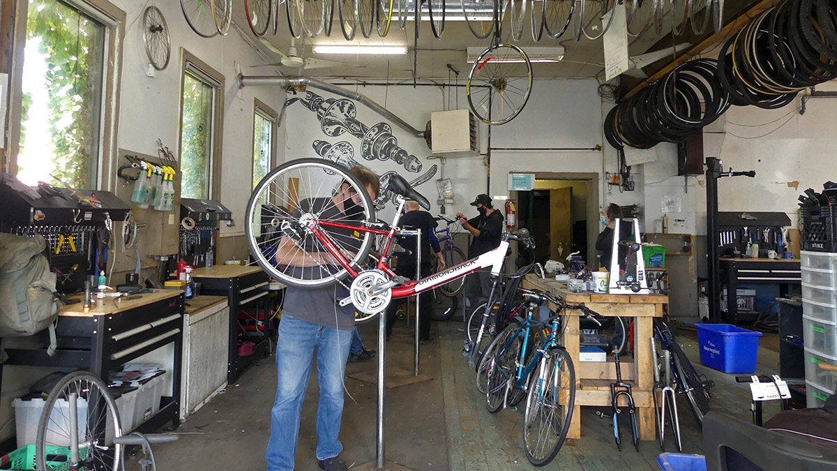 A Cycle Salvation staff member works on an elevated red bike in the shop