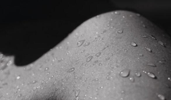 A shoulder with droplets is seen in black and white