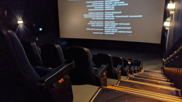 image of a movie theatre showing the back of the seats, with movie credits rolling on the screen
