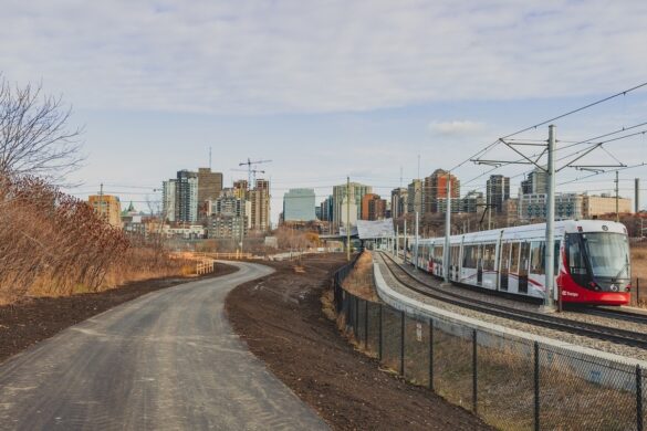 Image of new pathway along O-Train tracks through the LeBreton Flats area of the city with a train driving by.