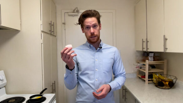 Reporter Zac Delaney is in his kitchen holding up an eggshell and making a face like he's asking a question.
