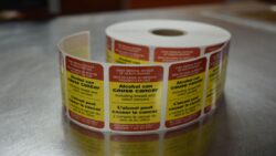 A roll of labels warning that alcohol can cause cancer.
