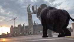 A virtual mammoth faces Parliament Hill with virtual snowfall.