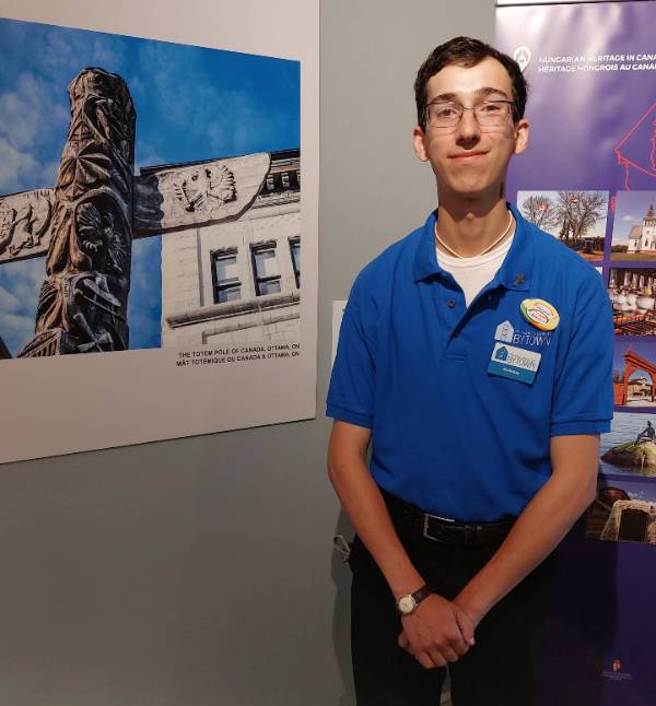 Nicholas Litardi stands in front of a poster with a totem pole.