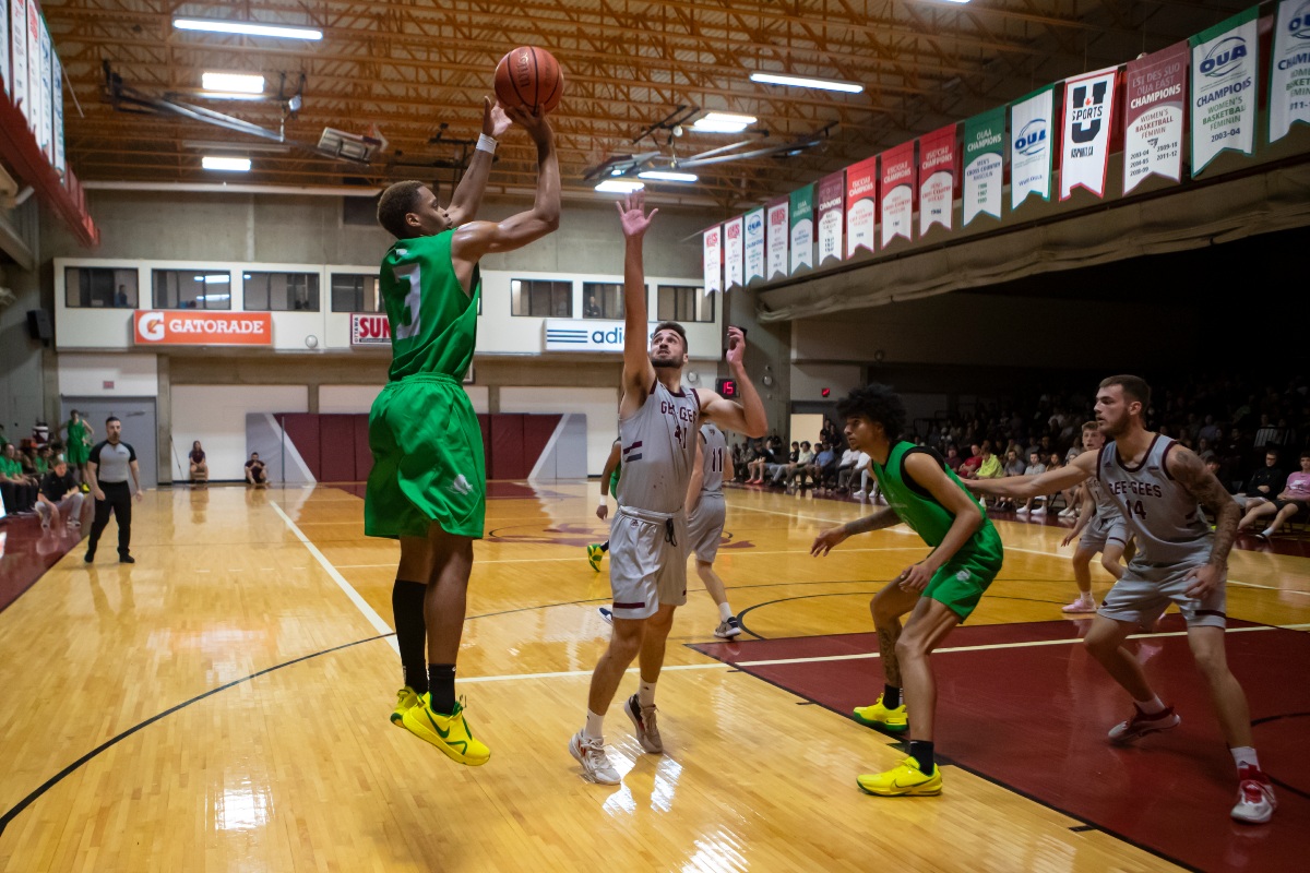 Oregon Ducks basketball forward Quincy Guerrier jumps to take a shot while University of Ottawa player Guillaume Pepin raises his arm to try blocking the shot.
