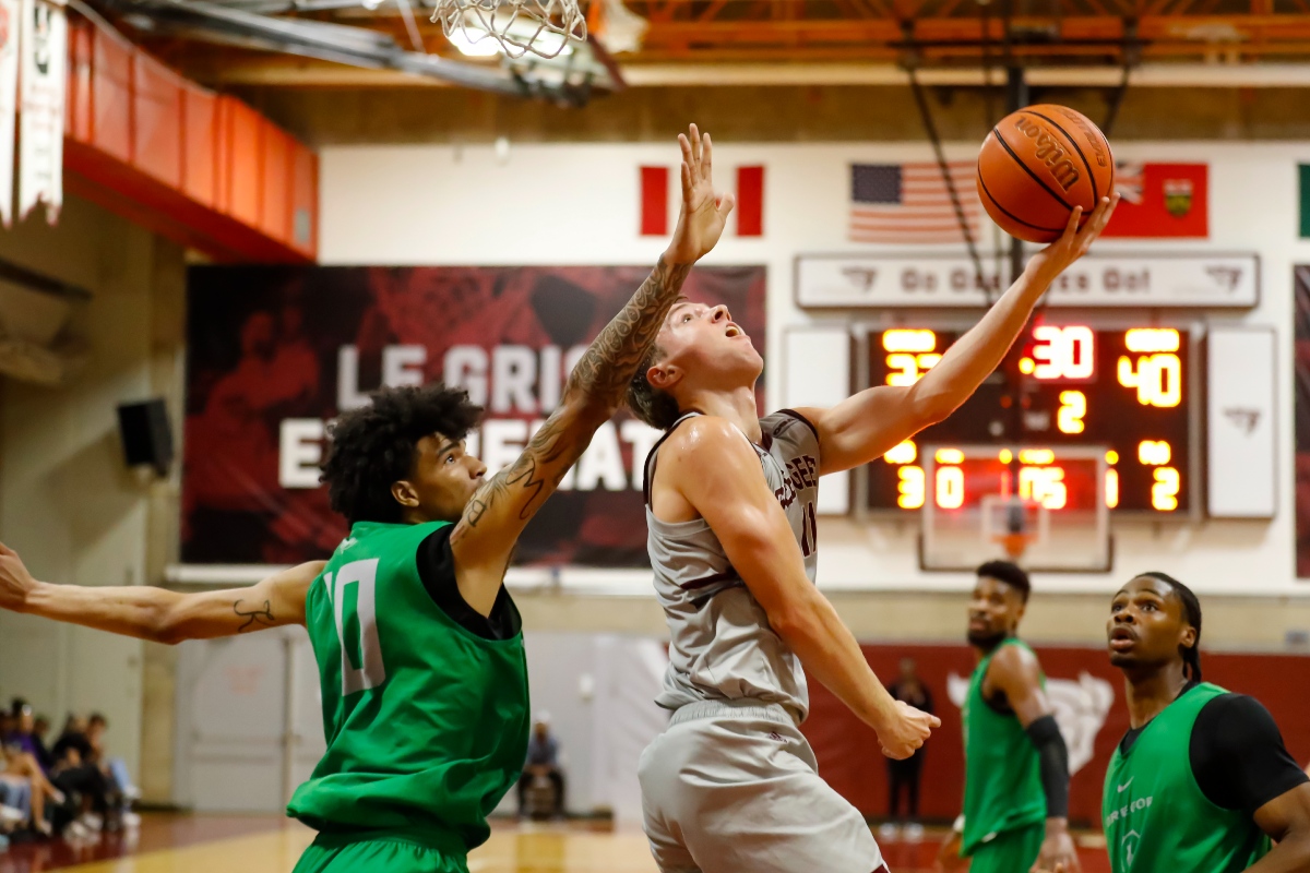 University of Ottawa basketball forward Brock Newton attempts an underhand shot while an Oregon Ducks player lunges in to try blocking.