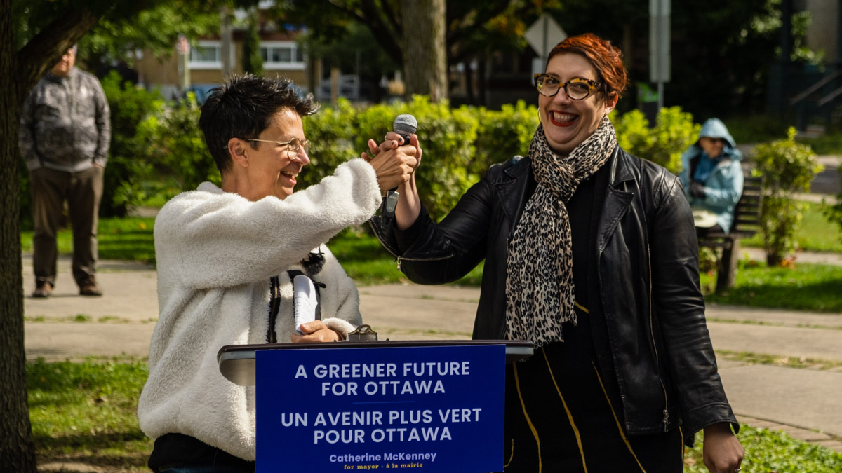 Somerset Coun. Catherine McKenney and candidate Ariel Troster exchange a microphone at a rally.