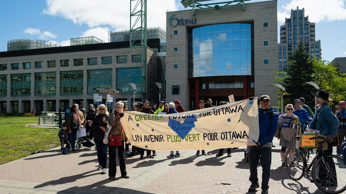 Members of the climate rally hold up a sign calling for "a greener future for Ottawa" in front of City Hall.