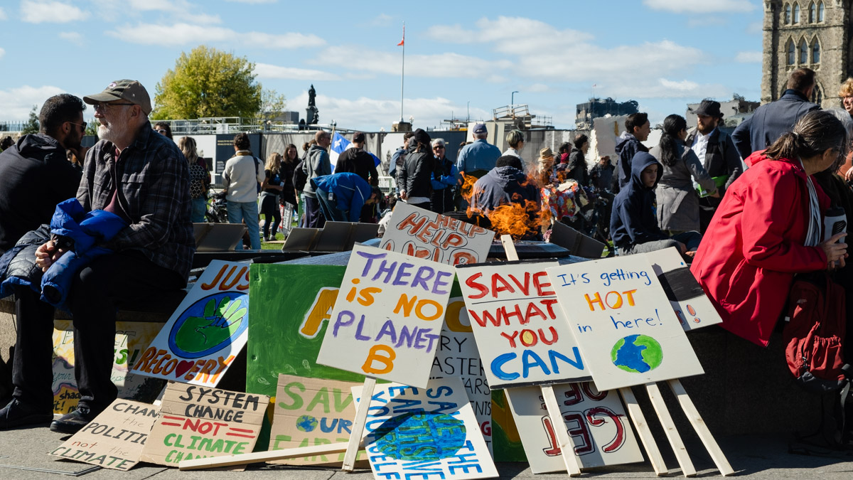 Signs calling for climate action sit in front of the Centennial Flame.