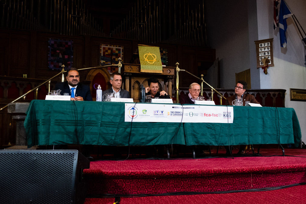 Ottawa's mayoral candidates sit at the mayoral debate as Catherine McKenney speaks.