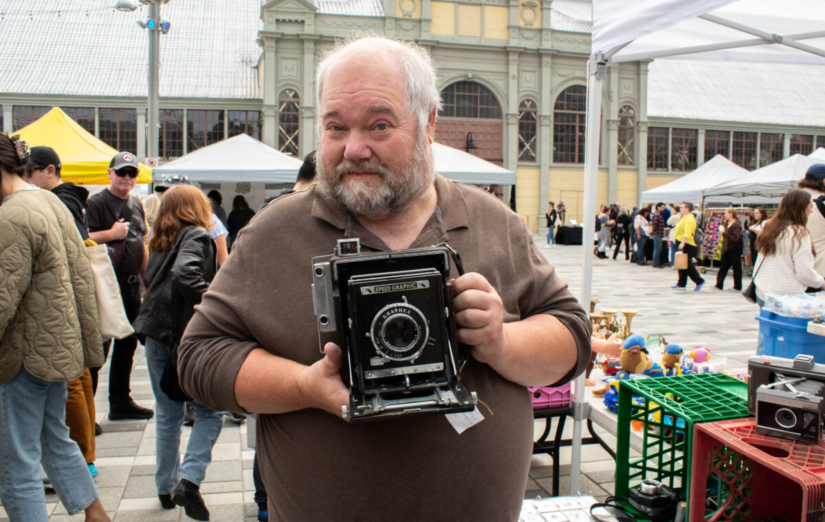 Jon Spence holds a old press film camera.