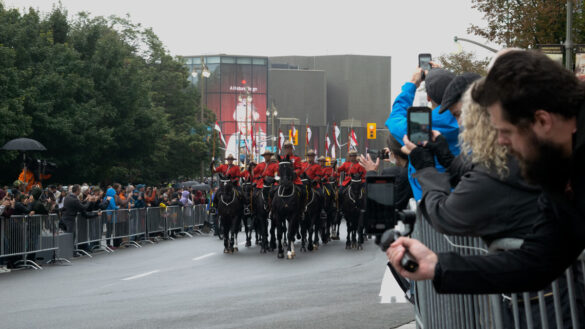 Man filming horses in memorial procession on tripod camera