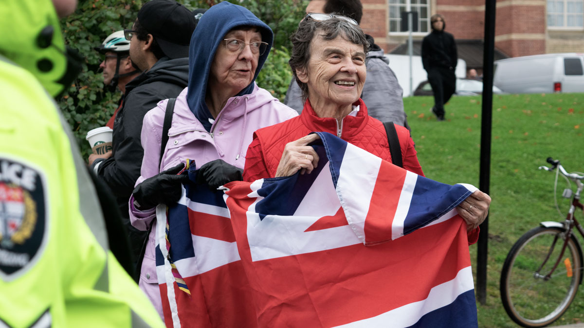 Two older women hold a British flag together.