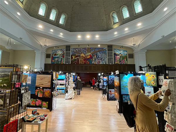 Rows of paintings set up in booths in open building space