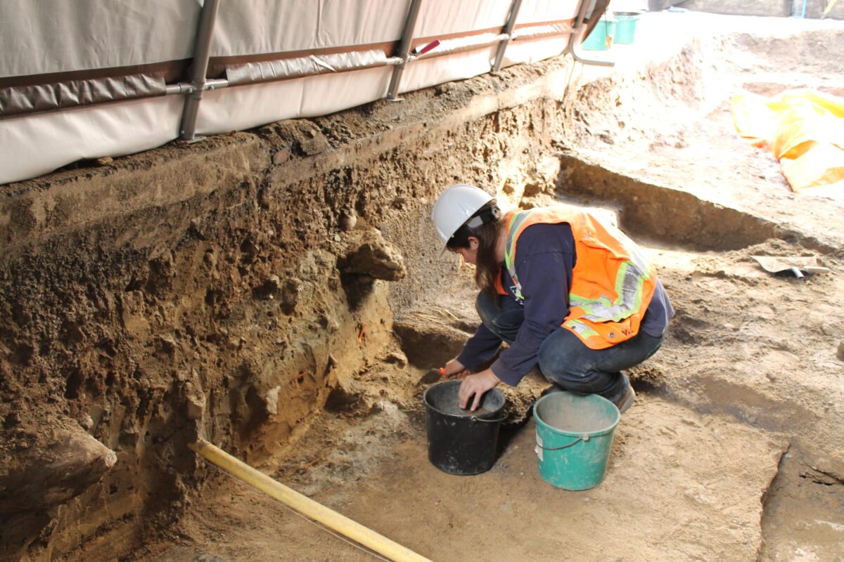 Archaeologist excavating Queen Street under shelter to protect the uncovered remains. 