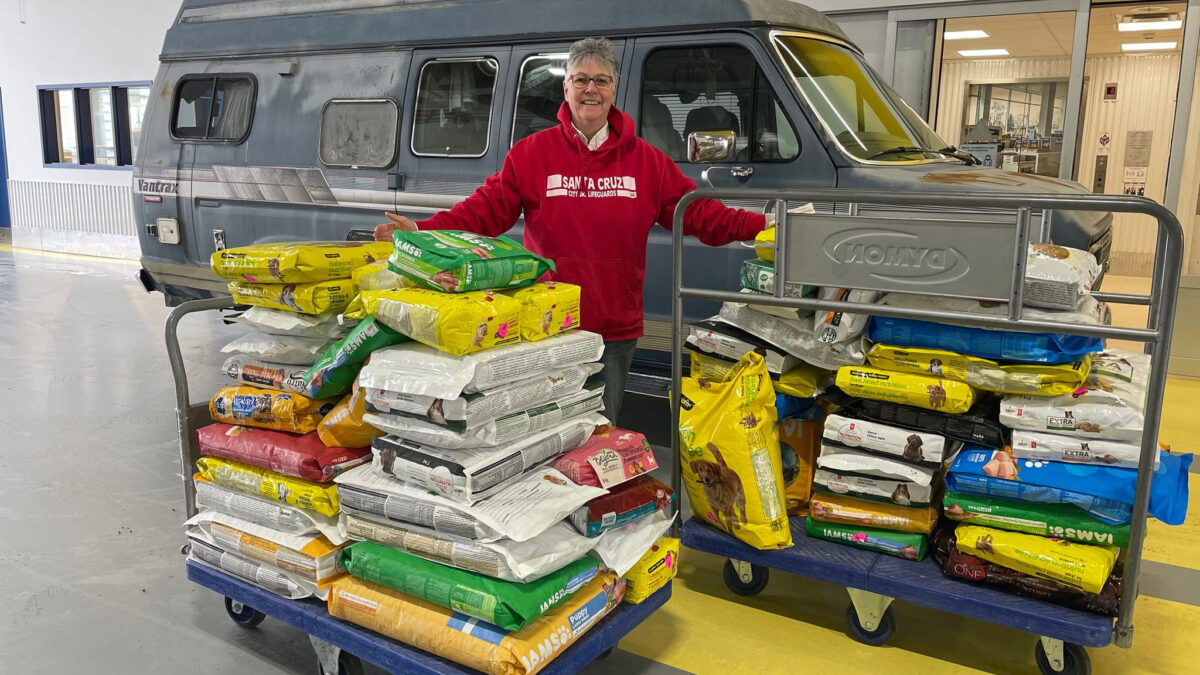 Woman with pet food donations, standing next to can.