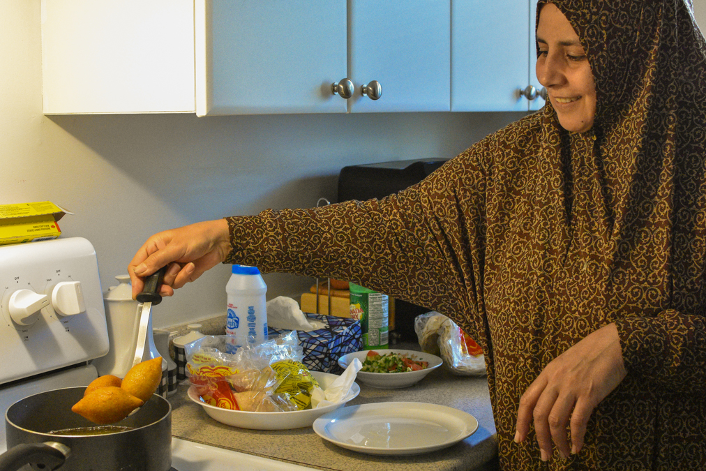 Ghusoun lifts fried kibbeh out of a pot of hot oil in her kitchen