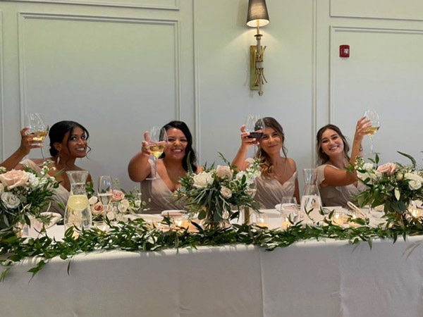 Four bridesmaids hold up wine glasses.